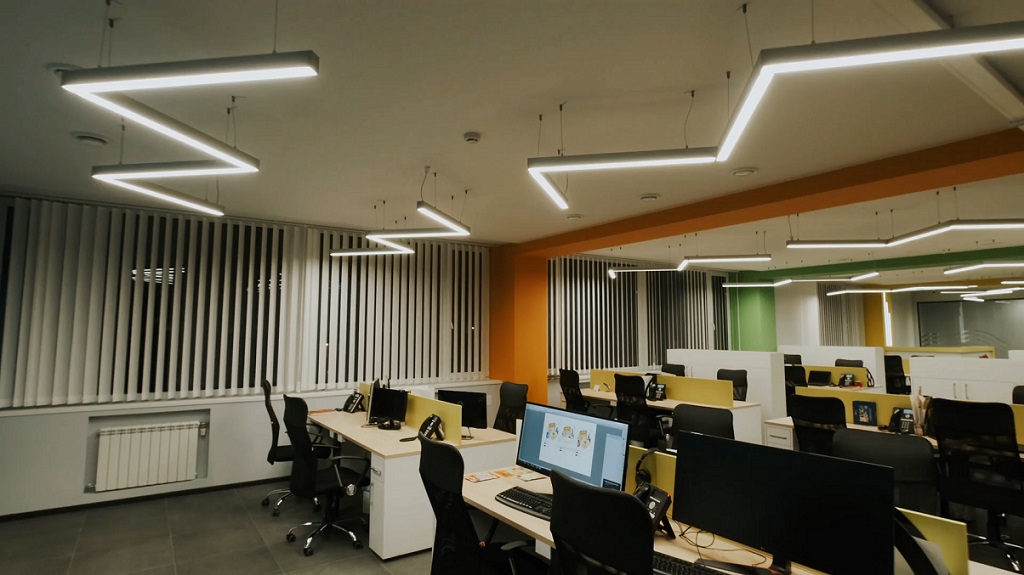 Moderna kancelarija sa LED rasvetom u obliku geometrijskih linija iznad radnih stolova